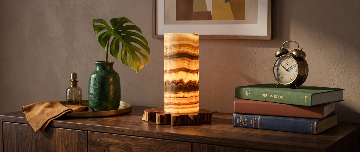 Decorative Sirelis table lamp with a stone pattern on a wooden chest of drawers surrounded by books, plants and accessories