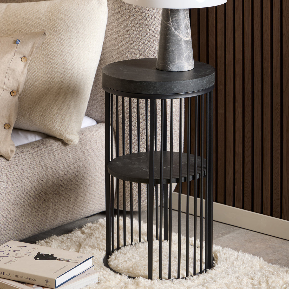 Cella Round Bedside Table with a Black Marble Effect, Modern Style – in a room setting