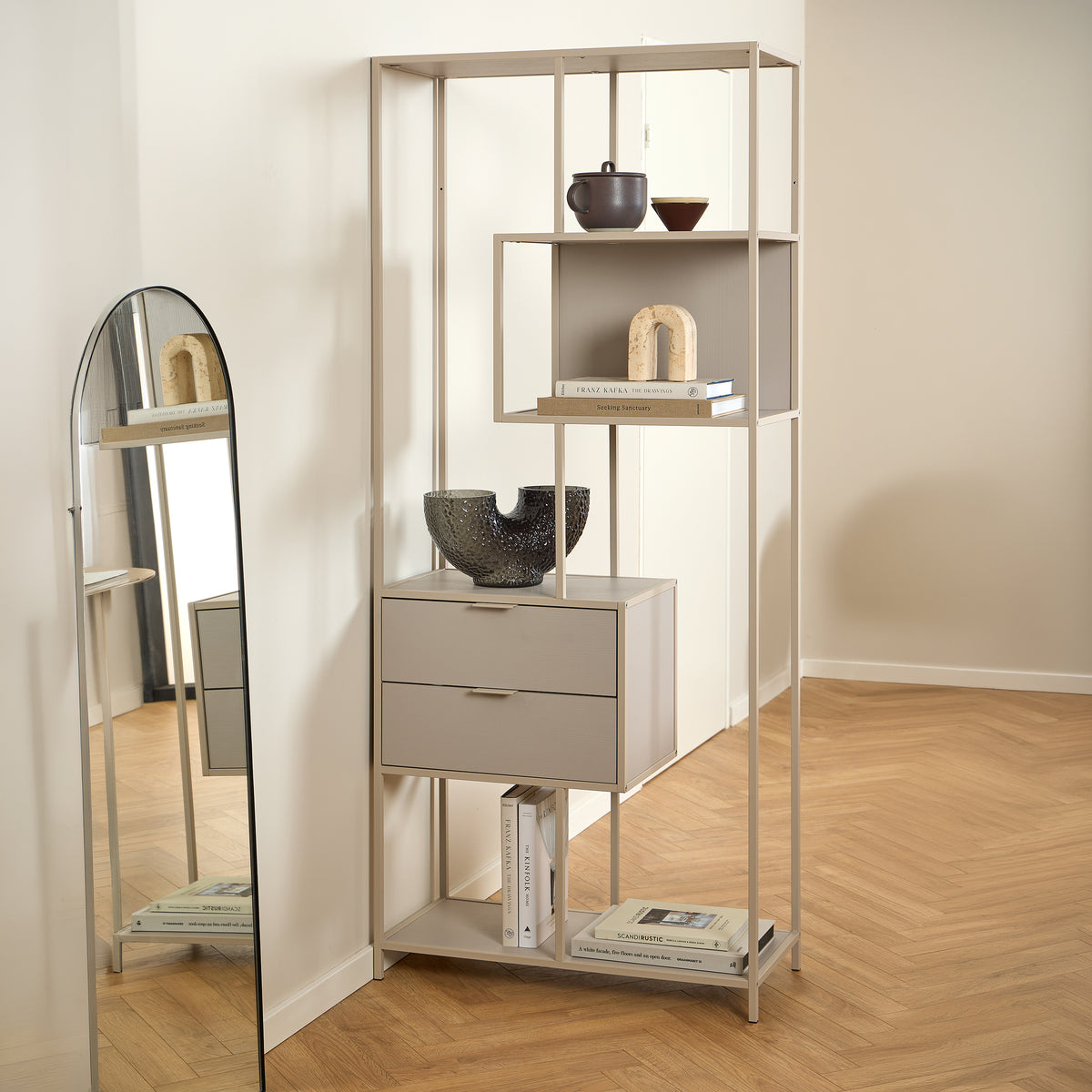 Skeleto-boekenkast 77x185 grijze melamine in een lichte kamer bij de spiegel, met keramiek en boeken
