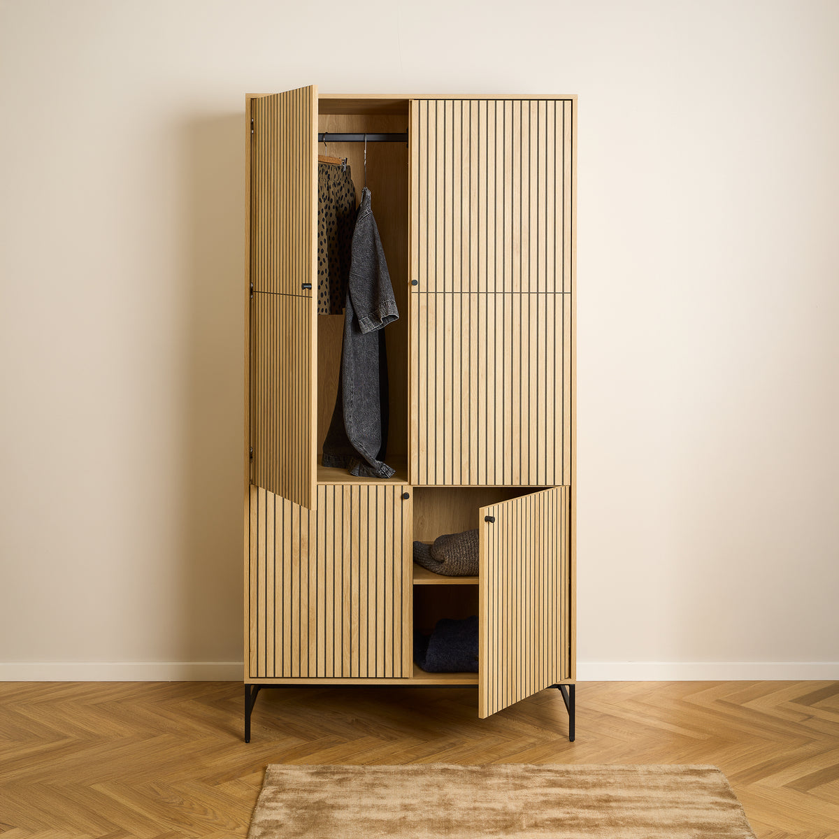 Bambouz-kast 99x200 op een vloer met visgraatpatroon – open deuren, kleding aan de stang en truien op de plank, kast voor de slaapkamer
