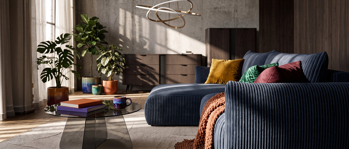 Moderne woonkamer met een donkerblauwe hoekbank Alloro, een glazen salontafel Aria Glass, donkere dressoirs Velia en een decoratieve hanglamp Movimento
