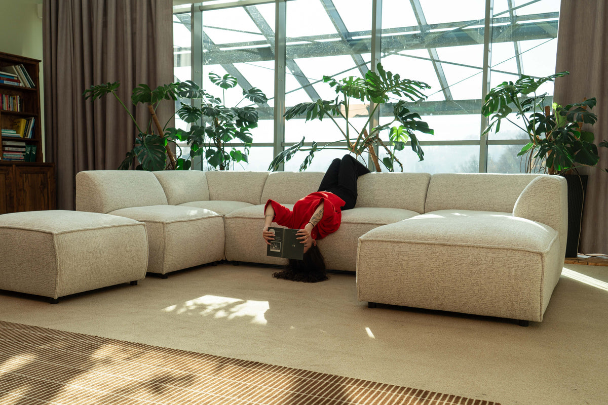 Une femme se détend sur un canapé modulaire Brick dans un intérieur lumineux rempli de plantes.