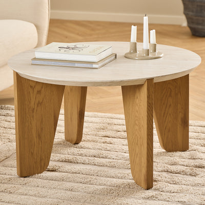 Table basse Tendra Ø80x45 posée sur un tapis beige, à côté d'un fauteuil clair, avec des livres et un bougeoir – table basse de salon